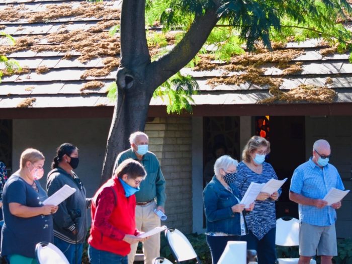 Group of standing people wearing face masks during outdoor church service in San Jose, CA