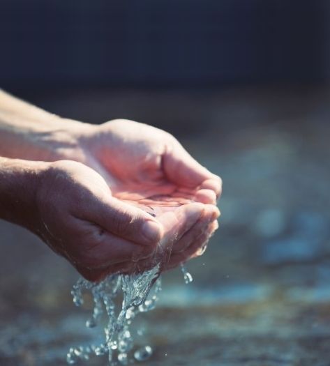 Priest pours water through hands for baptism