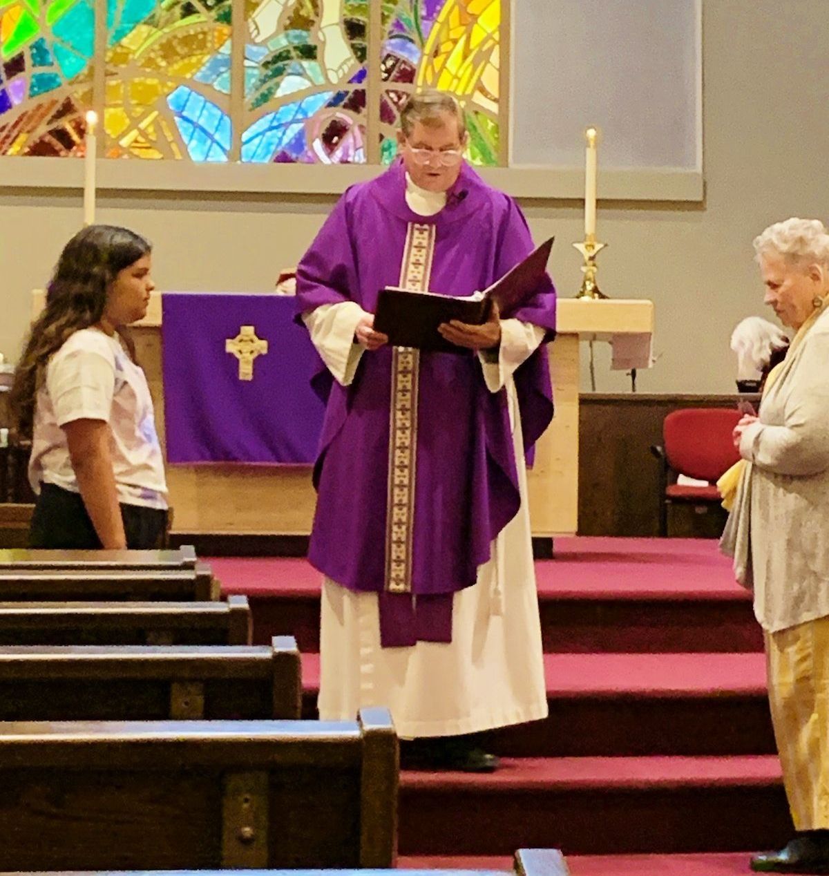 Young girl and adult woman stand with Priest during conformation ceremony