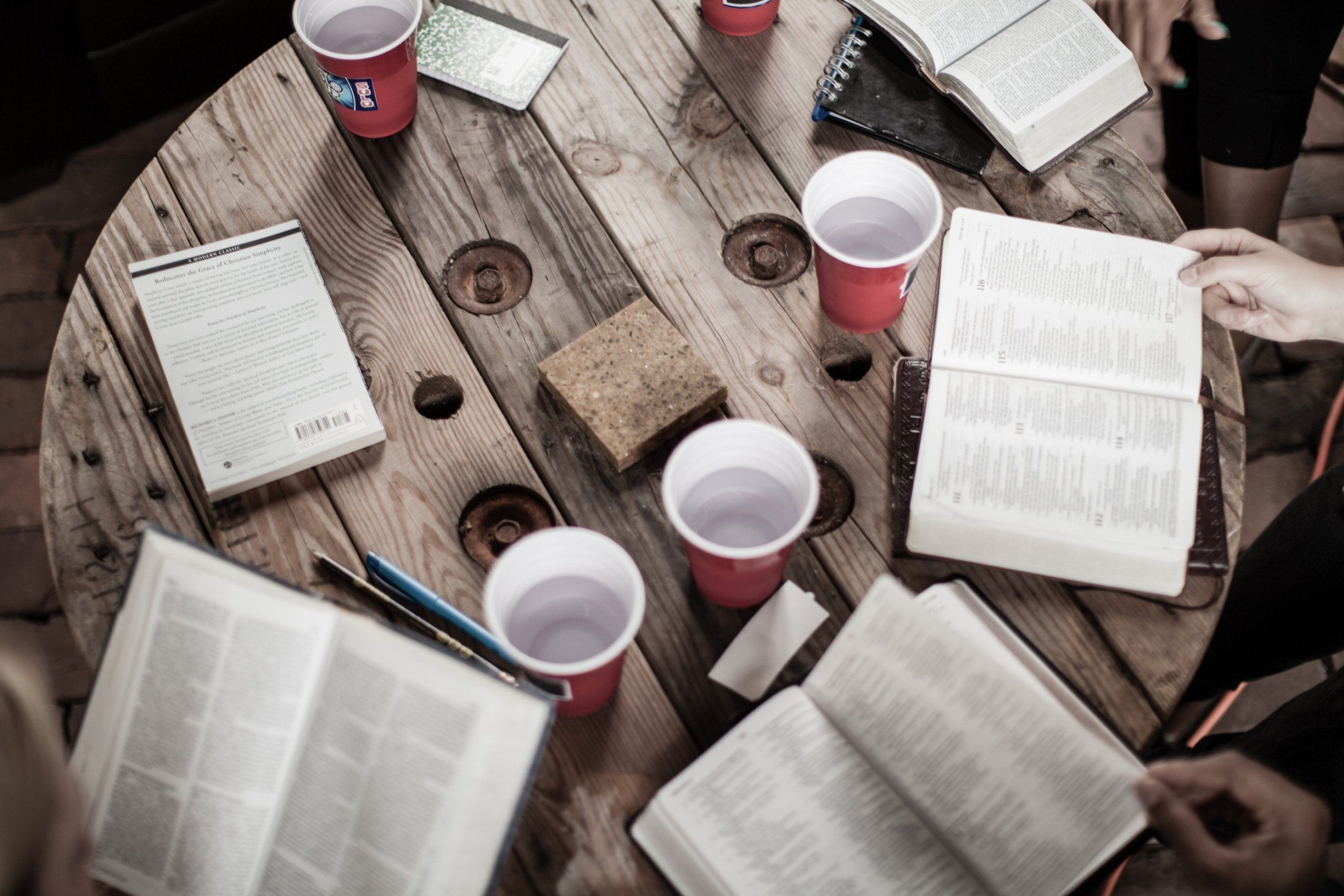 Multiple Bibles open on a wooden table for Bible study