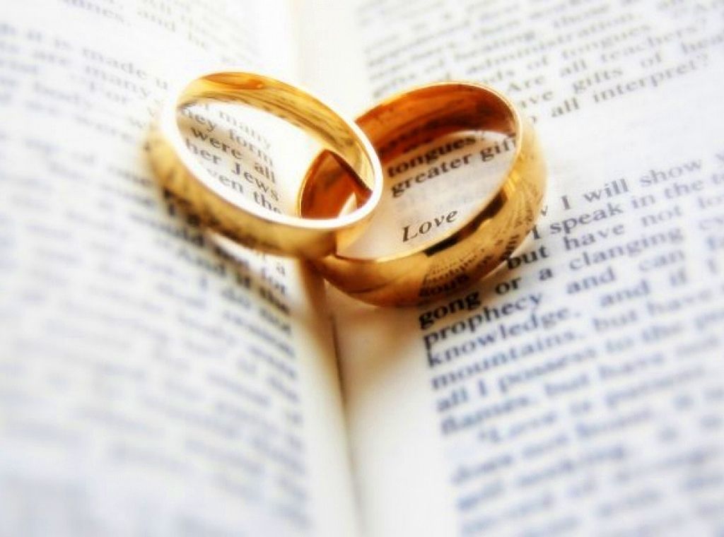 Two gold rings laying in the fold of an open Bible